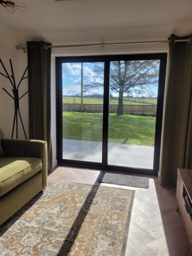 sun streams through glass patio doors into a living room. A rug adorns the floor