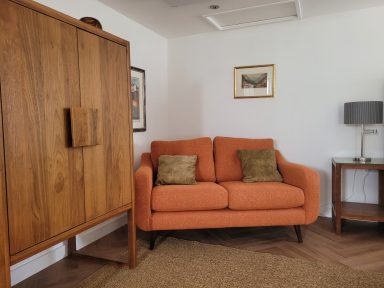 orange sofa sits between dark wooden furniture in a cosy family space.