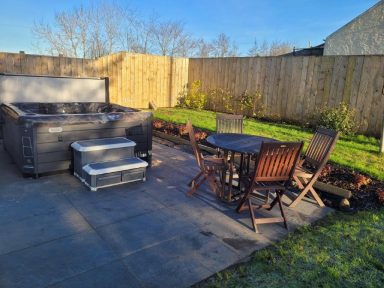 outdoor space, with a wooden table and chairs next to a modern hot tub.