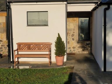 A wooden bench outside a stone cottage, drenched in sunlight