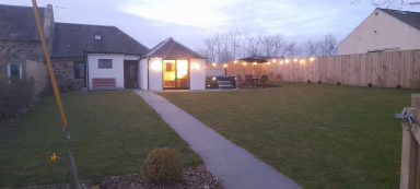 the cottage at dusk, with fairy lights surrounding the hot tub area