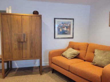 orange sofa sits next to dark wooden furniture in a cosy family space.